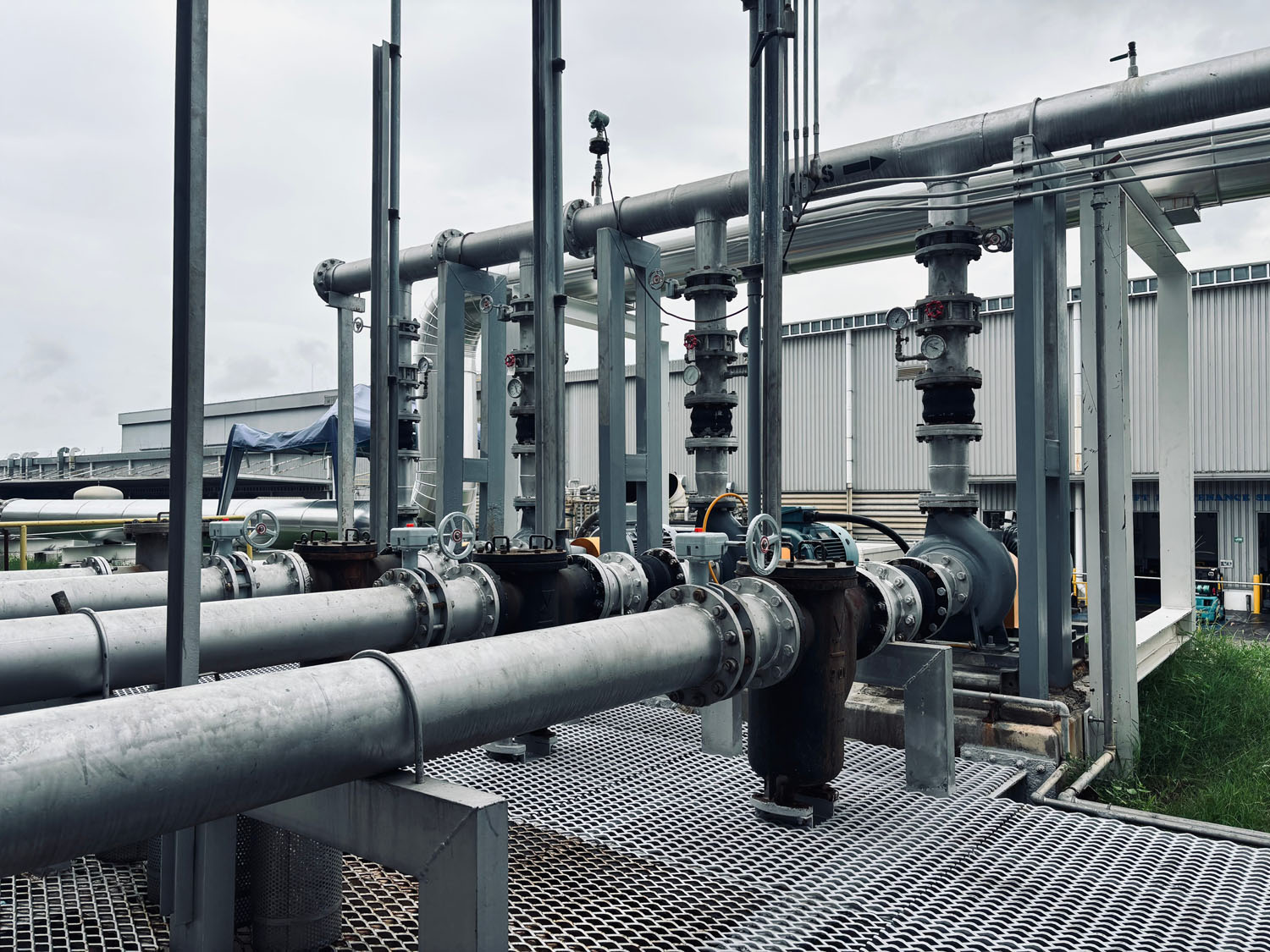 Outdoor network of industrial pipes and valves at a processing or energy facility.